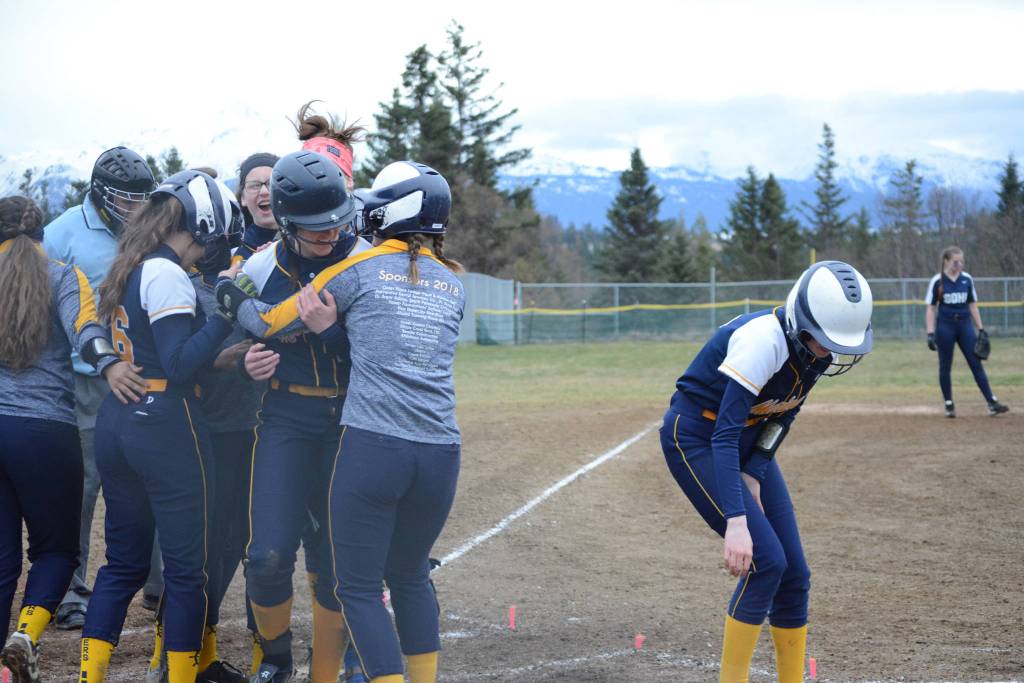 Homer High School Mariners softball batter Grace Godfrey gets a hug from her teammates after two other players scored on her hit on Tuesday, April 30, 2019, against Soldotna High School at Jack Gist Park in Homer, Alaska. (Photo by Michael Armstrong/Homer News)