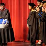 Kenai Peninsula Campus Director Gary Turner, left, reads a commendation awarding the title of Director Emerita to former Kachemak Bay Campus Director Carol Swartz, center, at the Kachemak Bay Campus commencement last Wednesday, May 8, 2019, at the Mariner Theatre in Homer, Alaska. Swartz retired last year. (Photo by Michael Armstrong/Homer News.)