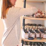 Britni Siekaniec, who owns and operates Alaska Salt Company with her husband Casey, arranges some merchandise on a shelf during the grand opening of the businesss new location on Friday, May 10, 2019 on the Homer Spit in Homer, Alaska.