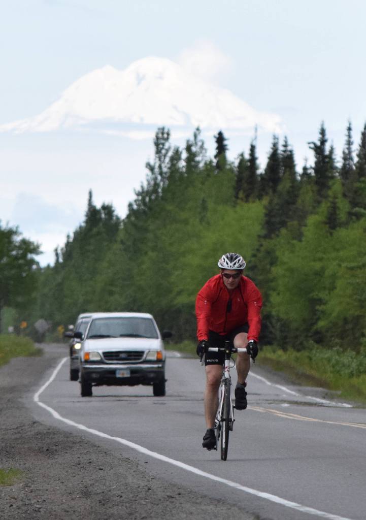 Anchorages John Krellner rides down Gas Well Road with Mount Redoubt in the background Sunday, June 9, 2019, in the Tri-The-Kenai Triathlon in Soldotna, Alaska. (Photo by Joey Klecka/Peninsula Clarion)