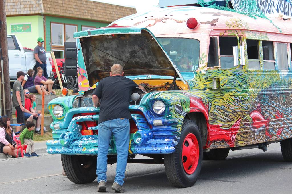 A participant in this years July Fourth parade pauses to make a quick fix to the bus used by the Center for Alaska Coastal Studies on Thursday, July 4, 2019 on Pioneer Avenue in Homer, Alaska. The bus roared to live shortly after and continued on its way through the parade route. (Photo by Megan Pacer/Homer News)
