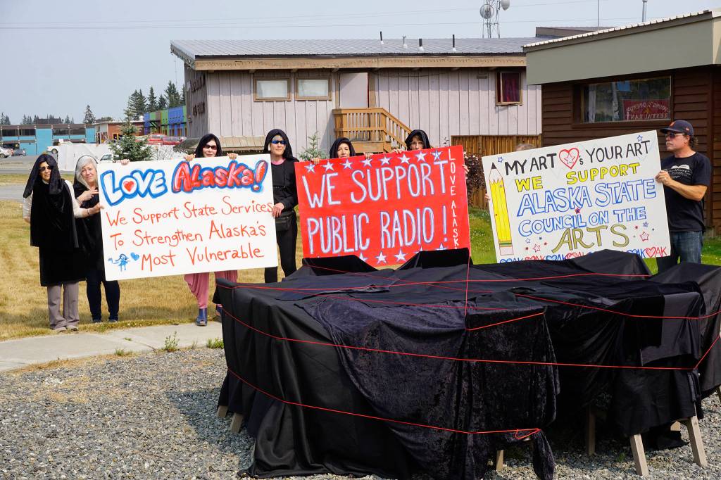 People draped in black hold signs on July 9, 2019, by Sean Derrys public art sculpture in Homer, Alaska, as part of a statewide art intervention to protest Gov. Mike Dunleavys veto of a $2.8 million state appropriation to the Alaska State Council on the Arts. They also supported a general override of Dunleavys vetoes that will affect funding for the University of Alaska, public radio and other programs. Derrys sculpture was commissioned as a 1% for art project associated with the remodeling of Pioneer Hall at the Kachemak Bay Campus, Kenai Peninsula College, University of Alaska. The protest was not sanctioned by the college. (Photo by Michael Armstrong/Homer News)