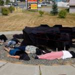 Photo by Michael Armstrong/Homer News                                People draped in black lie down on July 9 by Sean Derrys public art sculpture in Homer as part of a statewide art intervention to protest Gov. Mike Dunleavys veto of a state appropriation to the Alaska State Council on the Arts. They also supported a general override of Dunleavys vetoes that will affect funding for the University of Alaska, public radio and other programs. Derrys sculpture was commissioned as a 1% for art project associated with the remodeling of Pioneer Hall at the Kachemak Bay Campus, Kenai Peninsula College, University of Alaska. The protest was not sanctioned by the college.