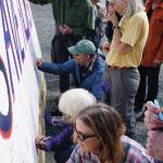 People respond to a prompt on a sign that reads Save Alaskas ____ at a rally Sunday, July 28, 2019, against Gov. Mike Dunleavys budget cuts at the Legislative Information Office, Homer, Alaska. (Photo by Michael Armstrong/Homer News).