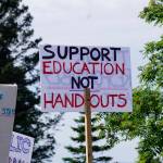 A demonstrator holds a sign at a rally Sunday, July 28, 2019, against Gov. Mike Dunleavys budget cuts at the Legislative Information Office, Homer, Alaska. (Photo by Michael Armstrong/Homer News).