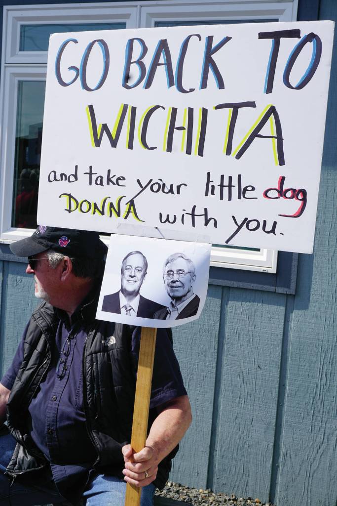 Darrell Oliver holds a sign with photos of the Koch brothers at a rally Sunday, July 28, 2019, against Gov. Mike Dunleavys budget cuts at the Legislative Information Office, Homer, Alaska. The Donna reference is to Office of Management and Budget Director Donna Arduin. (Photo by Michael Armstrong/Homer News).