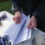 Recall Dunleavy organizer Kathy Carssow flips through pages of signed forms to get a tally at a Recall Dunleavy rally held on Aug. 1, 2019, at WKFL Park in Homer, Alaska. (Photo by Michael Armstrong)