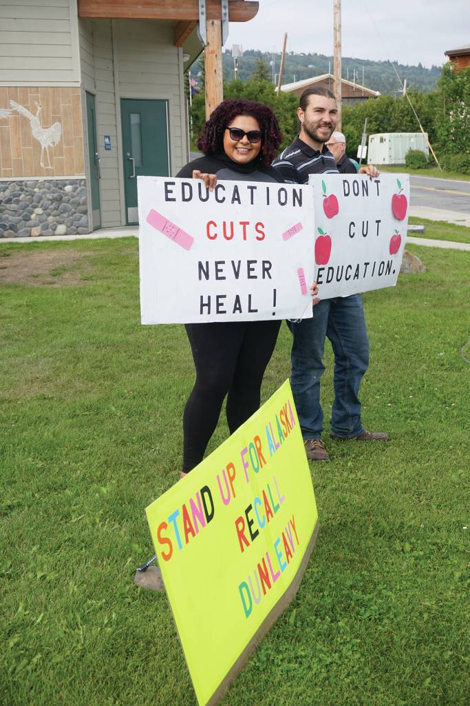 Xochitl Lopez-Ayala, left, and her husband, Don Horton, right, hold signs at a Recall Dunleavy rally held on Aug. 1, 2019, at WKFL Park in Homer, Alaska. (Photo by Michael Armstrong)