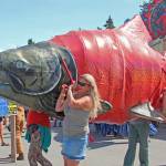 Volunteers carry a large salmon through the Ninilchik Fairgrounds during Salmonfest on Saturday, Aug. 3, 2019 in Ninilchik, Alaska. (Photo by Megan Pacer/Homer News)