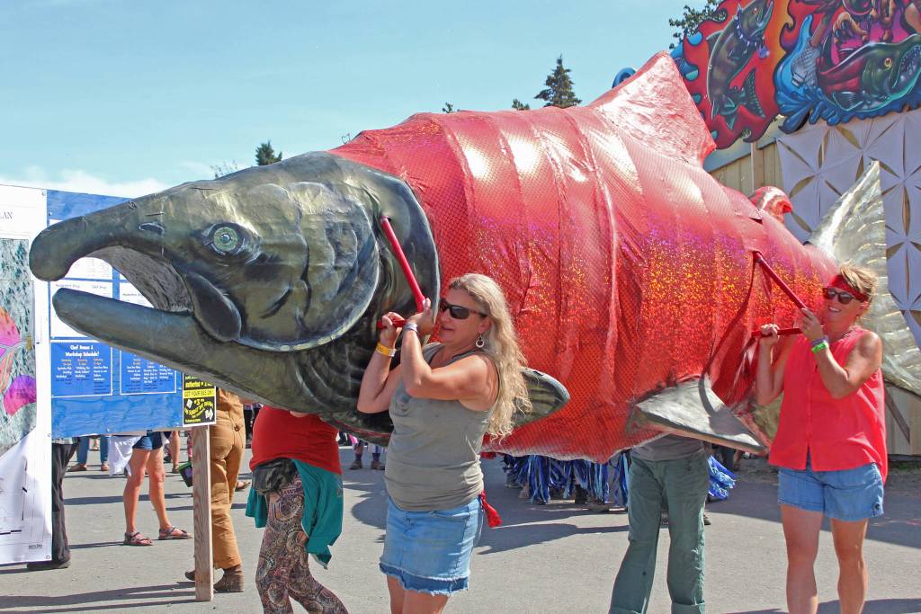 Volunteers carry a large salmon through the Ninilchik Fairgrounds during Salmonfest on Saturday, Aug. 3, 2019 in Ninilchik, Alaska. (Photo by Megan Pacer/Homer News)