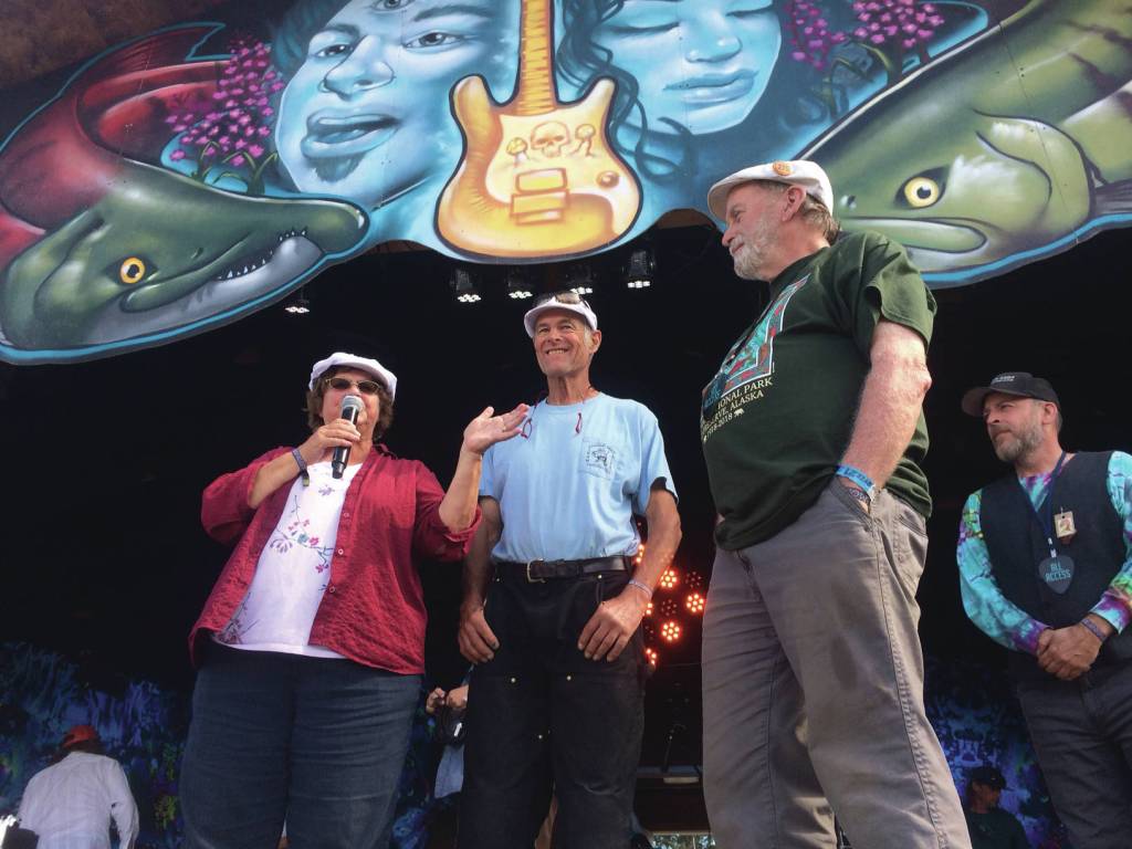 From left to right, Kate Mitchell, Dave Seaman and Tim Troll take to the main stage at Salmonfest on Sunday, Aug. 4, 2019, in Ninilchik, Alaska, to tell the crowd about Sailing Back to the Bay 2020. (Photo by McKibben Jackinsky)