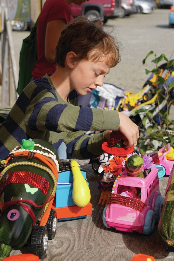 Kevin Talbot-Clark of Anchorage checks out the zucchini cars at the Homer Farmers Market on Saturday, Aug. 10, 2019, in Homer, Alaska. (Photo by Michael Armstrong/Homer News)
