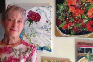 Debi Poore poses by some of the paintings in her show opening at the Homer Council on the Arts on Friday, Oct. 4, 2019, in Homer, Alaska. (Photo provided)