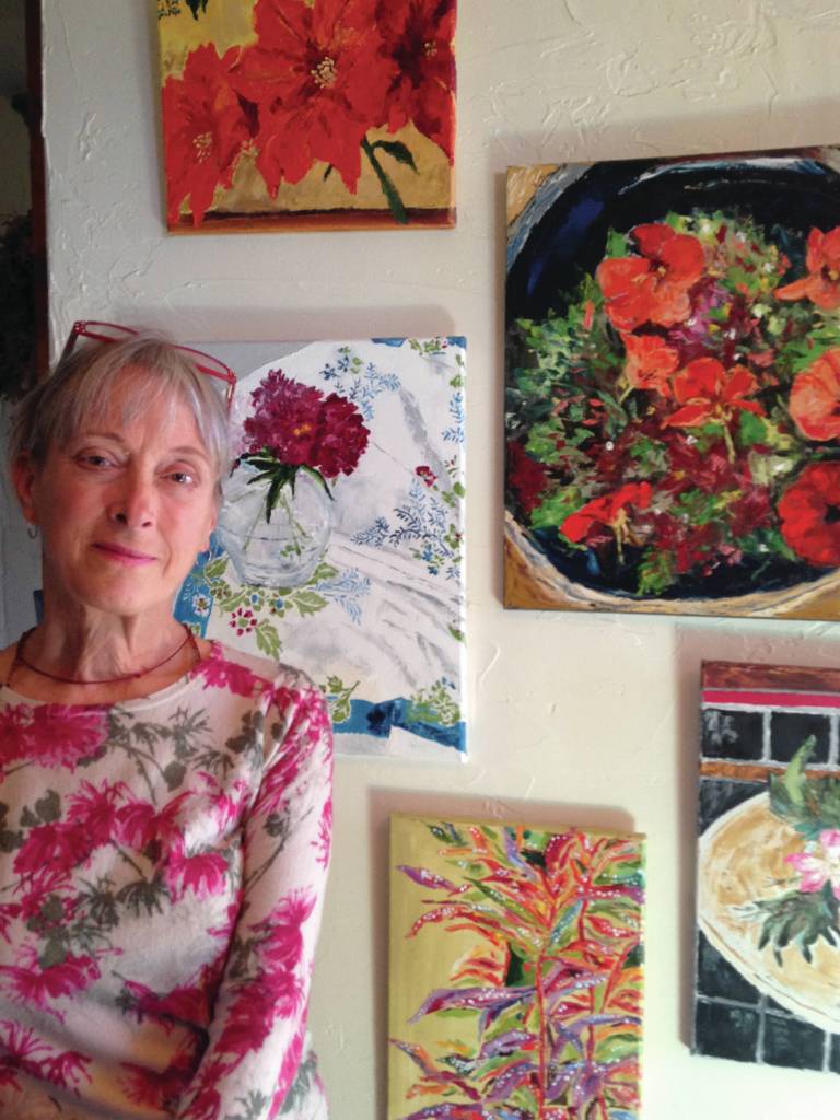 Debi Poore pose by some of the paintings in her show opening at the Homer Council on the Arts on Friday, Oct. 4, 2019, in Homer, Alaska. (Photo provided)
