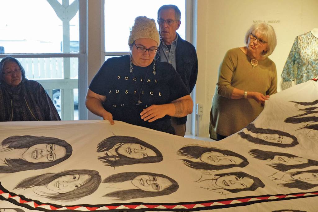 Amber Webb, center, discusses her kuspuk at the opening of the Kuspuk/Qaspeq/Atikluk show on Oct. 5, 2019, at Bunnell Street Arts Center in Homer, Alaska. The kuspuk shows faces of missing or murdered indigenous women. (Photo by Michael Armstrong/Homer News)