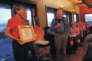 Ed Berg, right, accepts the Land at Heart Award from Nina Faust (left) and Marie McCarty (center) during the annual gala fundraiser event for the Kachemak Heritage Land Trust on Saturday, Oct. 12, 2019 at Wasabis Bistro in Homer, Alaska. (Photo by Megan Pacer/Homer News)