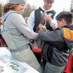 Alaska Department of Fish and Game biologists Holly Dickson (left) and Andrew Waldo (center) help Chapman School second grader Khian Tangnon (right) empty the milt from a male salmon into a pitcher of salmon eggs during the annual egg take event at the Anchor River on Thursday, Oct. 10, 2019 in Anchor Point, Alaska. The egg take is the first phase in the Salmon in the Classroom project. (Photo by Megan Pacer/Homer News)