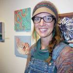 Jamie Cloud poses next to her paintings, some of the works of art in the 10x10 show at Bunnell Street Arts Center that opened on Nov. 8, 2019, in Homer, Alaska. (Photo by Michael Armstrong/Homer News)