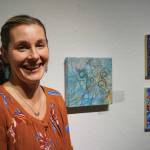 Brianna Lee stands by her painting, Cipher, one of the works of art in the 10x10 show at Bunnell Street Arts Center that opened on Nov. 8, 2019, in Homer, Alaska. (Photo by Michael Armstrong/Homer News)