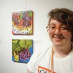 Drew Wimmerstedt stands by two of her works in the 10x10 show at Bunnell Street Arts Center that opened on Nov. 8, 2019, in Homer, Alaska. (Photo by Michael Armstrong/Homer News)