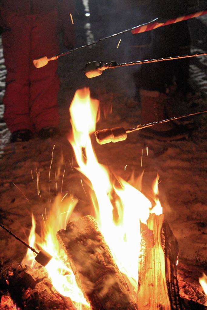 Community members roast marshmallows over a fire to make smores during this years Holiday Tree Lighting event Thursday, Dec. 5, 2019 at the Homer Chamber of Commerce and Visitor Center in Homer, Alaska. (Photo by Megan Pacer/Homer News)