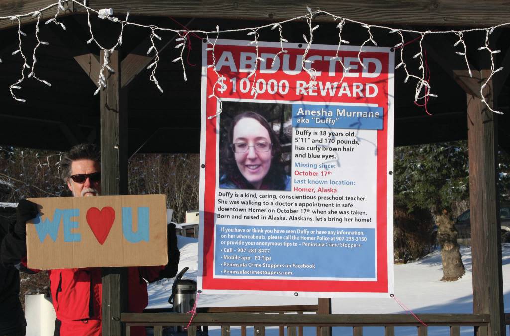 Wes Schacht, a friend and tenant of Sara and Ed Berg, stands next to a missing poster of Anesha Duffy Murnane in the gazebo at WKFL Park during a candlelight vigil in Homer, Alaska, on Saturday, Feb. 1, 2020. (Photo by Delcenia Cosman)