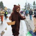 A parade marcher in a bear costume hands out goodies to families attending this years Homer Winter Carnival on Saturday, Feb. 8, 2020 on Pioneer Avenue in Homer, Alaska. (Photo by Megan Pacer/Homer News)