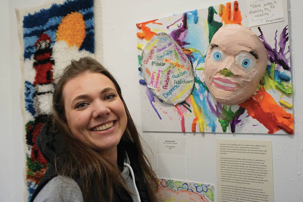 Cora Trowbridge stands by her art, Behind the Mask, on March 6, 2020, at the Disability Art Show at the Homer Council on the Arts in Homer, Alaska. (Photo by Michael Armstrong/Homer News)