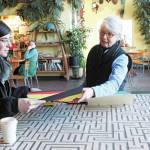 Artist Gail Baker, who previously lived in Homer, speaks to a parent about the student art done by Fireweed Academy students during her Artist in the Schools Program residency, at an art exhibit opening Thursday, March 5, 2020 at K-Bay Caffe in Homer, Alaska. The students created decorative masks under her direction. (Photo by Megan Pacer/Homer News)