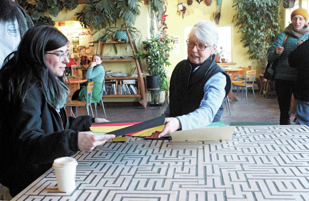 Artist Gail Baker, who previously lived in Homer, speaks to a parent about the student art done by Fireweed Academy students during her Artist in the Schools Program residency, at an art exhibit opening Thursday, March 5, 2020 at K-Bay Caffe in Homer, Alaska. The students created decorative masks under her direction. (Photo by Megan Pacer/Homer News)