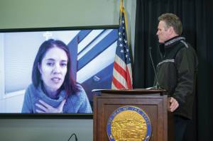 Alaska Chief Medical Officer Dr. Anne Zink, left, speaks by video in a press conference on April 6, 2020, in Juneau, Alaska, while Gov. Mike Dunleavy, right, listens. (Photo by Austin McDaniel, Alaska Governors Office)