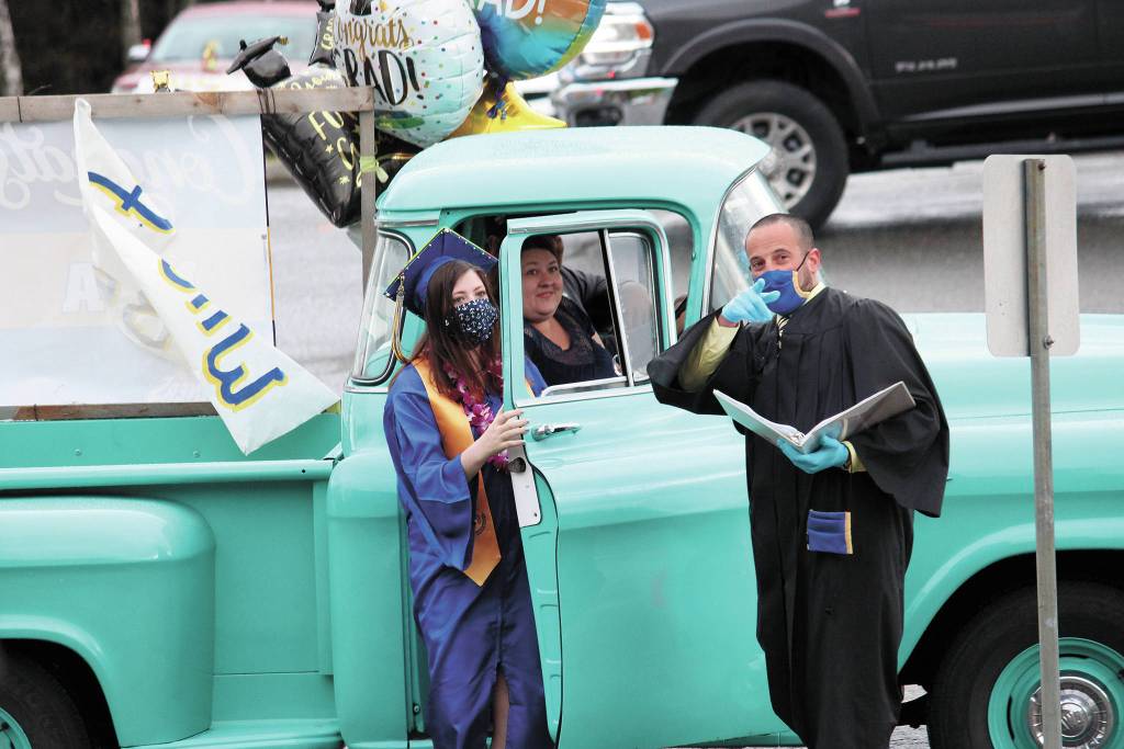 School Counselor Paul Story points graduate Mya Betts to the path she needs to take to the stage set up outside of Homer High School as she prepares to collect her diploma during a drive-through commencement ceremony Monday, May 18, 2020 in Homer, Alaska. Graduates exited their vehicles in front of the school, crossed the stage to get their diplomas and got back into their vehicles before taking part in a procession through town. (Photo by Megan Pacer/Homer News)