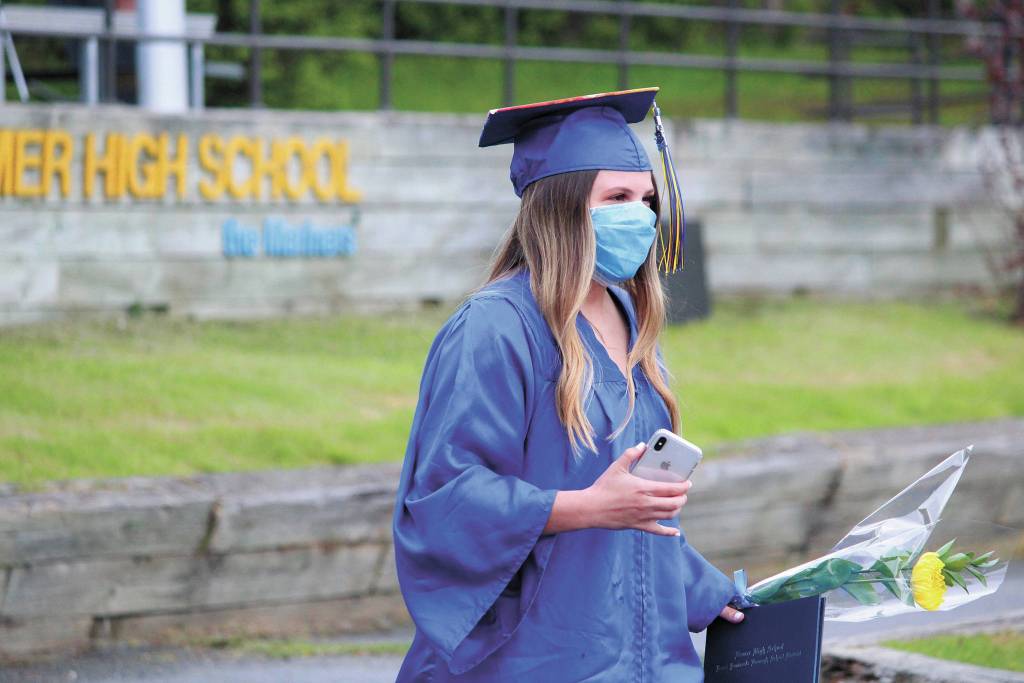 Graduate Rylee Doughty walks back to her family and their vehicle after getting her diploma during Homer High Schools drive-through commencement ceremony Monday, May 18, 2020 at the school in Homer, Alaska. (Photo by Megan Pacer/Homer News)