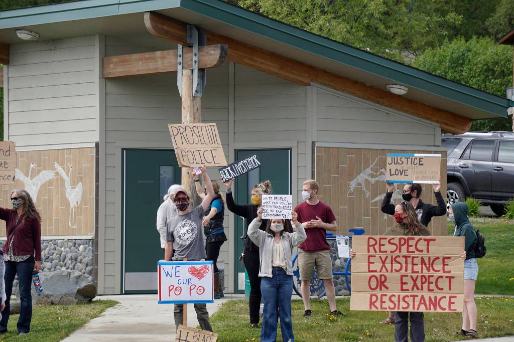 In front and from left to right, Aaron Ford, Karianna Ford and Jenni Stowe hold signs at a protest on Sunday, May 30, 2020, at WKFL Park in Homer, Alaska, in support of people of color who have been the subject of police violence, including George Floyd, a man who died May 25, 2020, in a police encounter in Minneapolis, Minnesota. In addition to the We (heart) our po po sign  po po is slang for police  there also was a sign that read Thank you HPD. (Photo by Michael Armstrong/Homer News)