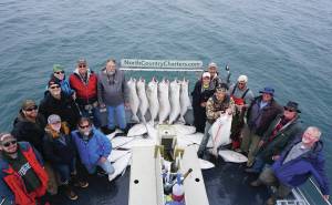Anglers stand by a rack of halibut on the Irish as the North Country Charters boat returned to Homer in July 2017. (Photo by Michael Armstrong/Homer News file photo)