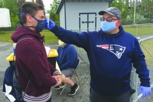 Soldotna assistant football coach Eric Pomerleau checks the temperature of sophomore Joseph Whittom before summer workouts Wednesday, June 17, 2020, at Soldotna High School in Soldotna, Alaska. (Photo by Jeff Helminiak/Peninsula Clarion)