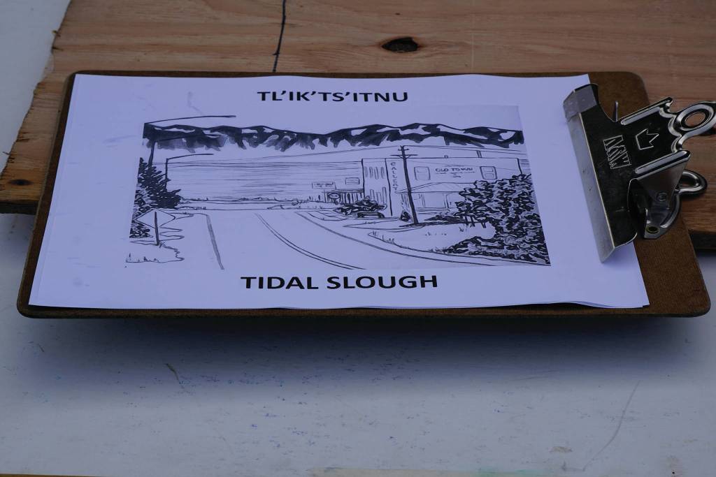 A clipboard shows the Denaina word for tidal slough, Tliktsitnu with an illustration of the Old Town area of Homer. It was part of the material used in Land Acknowledgement in Action: Sign Installation last Saturday, Aug. 22, 2020, at the Bishops Beach pavillion  the area known by the Denaina people as Tuggeht, or at the water. (Photo by Michael Armstrong/Homer News.)
