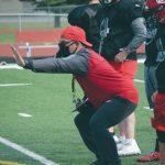 Photo by Jeff Helminiak/Peninsula Clarion                                 Kenai Central football coach Travis Akana coaches blocking technique as Jackson DuPerron looks on during practice Monday, Aug. 31, at Ed Hollier Field at Kenai Central High School in Kenai.