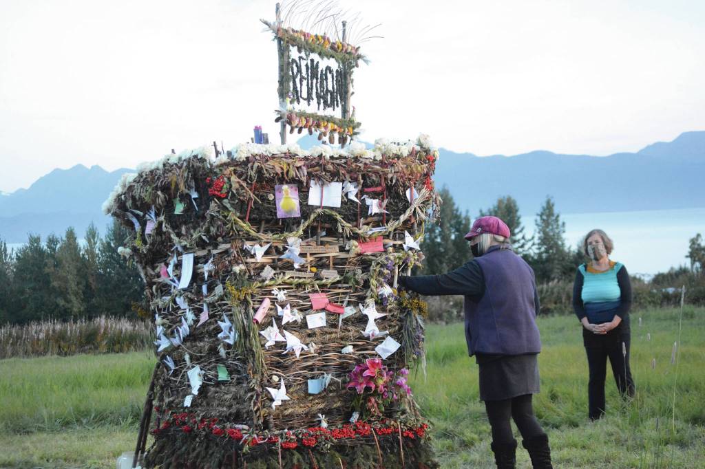 As Peggy Paver right, watches, Mavis Muller, left, places a note inReimagine, the 17th annual Burning Basket, in a field on Sunday, Sept. 13, 2020, near Homer, Alaska. Artist and coordinator Muller intended to broadcast live on Facebook and YouTube the burning of the basket, but because of technical difficulties that didnt happen. Burning Basket teaches how to let go of expectations and accept the present moment, Muller wrote in a text message. Technology is fickle. The basket, however, did exactly what it promised to do. It helod our collective burderns, our memorials, our joys, sadness, fear, and dispersed all of our good intentions in a plume of smoke, sparks and flames. (Photo by Michael Armstrong/Homer News)