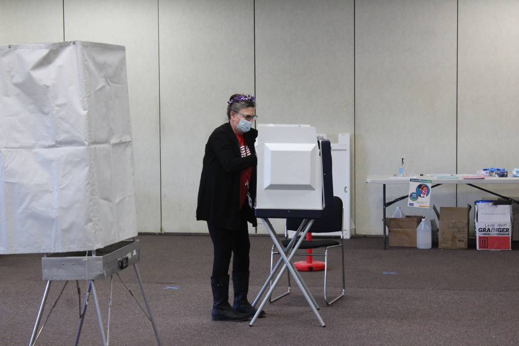 A poll worker is seen disinfecting a voting booth at the Soldotna Regional Sports Complex on Tuesday, Nov. 3 in Soldotna, Alaska. (Photo by Ashlyn OHara/Peninsula Clarion)