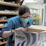 South Peninsula Pharmacist Jill Kort peers into a box filled with 180 doses of the Pfizer vaccine for COVID-19 shortly after it arrived at the hospital on Wednesday, Dec. 16, 2020 in Homer, Alaska. (Photo by Megan Pacer/Homer News)