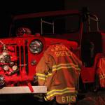 The firefighter uniforms for Gary Thomas, a former volunteer firefighter who was killed in a water heater explosion this month, hang on an antique fire truck in the Homer Mariner Theatre during a memorial for Thomas on Sunday, Jan. 19, 2020 at Homer High School in Homer, Alaska. (Photo by Megan Pacer/Homer News)
