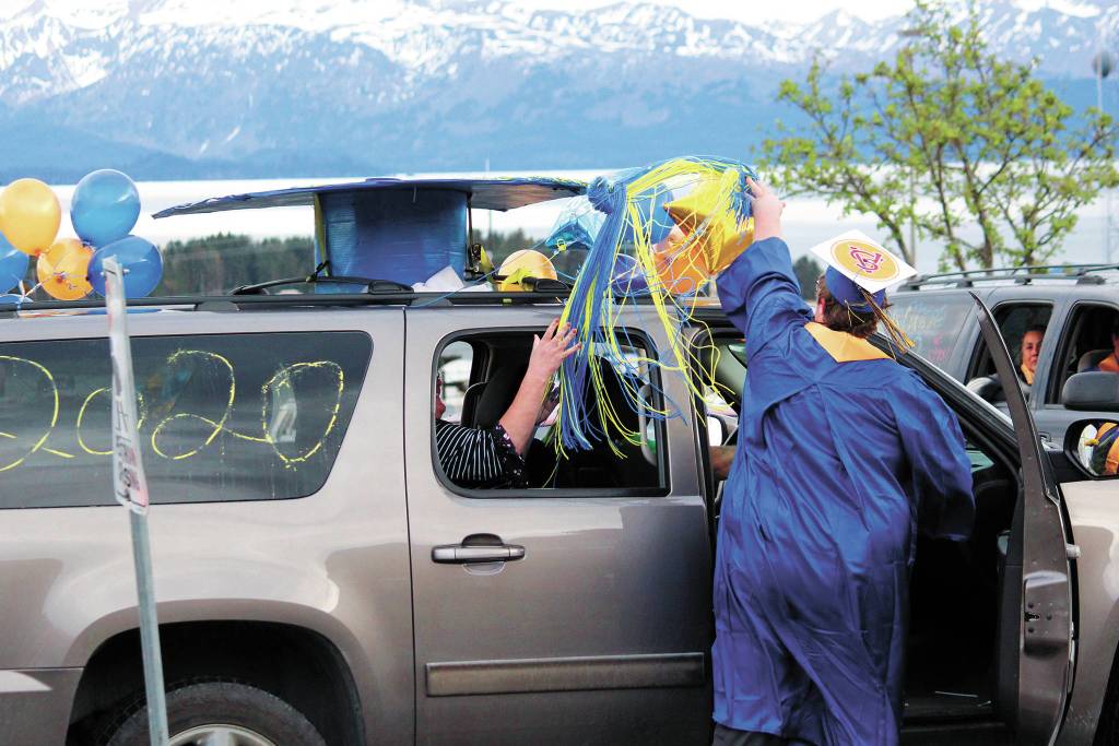 Graduate Colby Marion moves the tassel on a giant graduation cap atop his familys vehicle after collecting his diploma at Homer High Schools drive-through commencement ceremony Monday, May 18, 2020 at the school in Homer, Alaska. (Photo by Megan Pacer/Homer News)