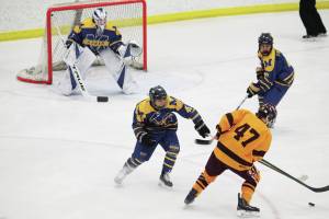 Homers Bergen Knutson (left) and Toby Nevak (right) try to fend off Dimonds Kaden Daniels during a Friday, Feb. 14, 2020 game at the 2020 ASAA First National Cup Division I Hockey State Championship at the Curtis D. Menard Memorial Sports Center in Wasilla, Alaska. (Photo by Megan Pacer/Homer News)