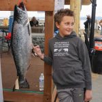 Andrew Marley, the 2021 Homer Winter King Salmon Tournament winner, points to his prize winning 25.62-pound white king salmon on Saturday, April 17, 2021, on the Homer Spit in Homer, Alaska. (Photo by Michael Armstrong/Homer News)
