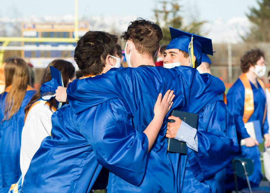 Three Homer High seniors embrace after graduating on May 18. (Photo by Sarah Knapp/Homer News)