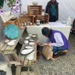 A customer views the coffee mugs available for sale at a booth at the farmers market on May 29.