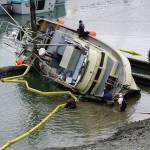 Workers respond to a fishing boat, the F/V Redoubt, that ran aground on the wooden grid on Wednesday, June 2, 2021, in the Homer Harbor in Homer, Alaska. The boat heeled over as the tide went out. (Photo by Michael Armstrong/Homer News)