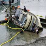 Workers respond to a fishing boat, the F/V Redoubt, that ran aground on the wooden grid on Wednesday, June 2, 2021, in the Homer Harbor in Homer, Alaska. The boat heeled over as the tide went out. (Photo by Michael Armstrong/Homer News)