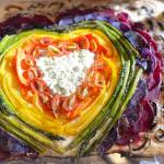 Photo by Tressa Dale/Peninsula Clarion 
Feta and Parmesan cheese, cherry tomatoes, carrot, yellow bell pepper, asparagus, purple potatoes, beets and white button mushrooms are shaped into a rainbow with a cheesy heart on top of focaccia bread.